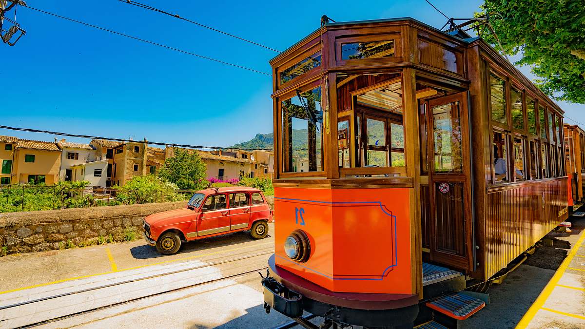 tram red train passing through rails beside red vehicle spain